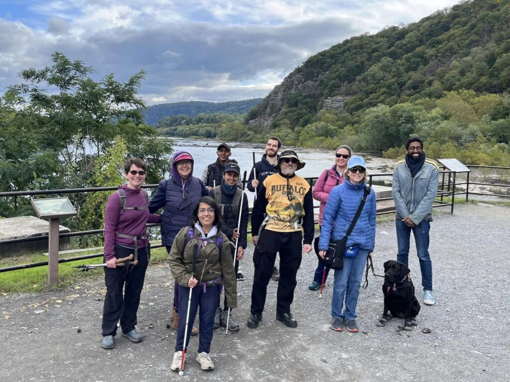 Ten hikers and stand smiling at a trailhead.