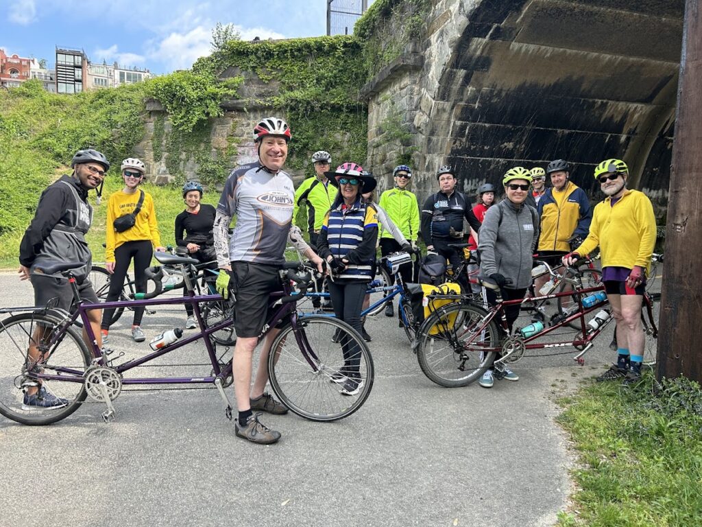 On a break during one of our tandem bike rides in April, 16 cyclists gathered for a group photo at the start of the Capital Crescent trail in Georgetown. Shown, from left to right, are Nafij, Kay, Ariel, Dave, Ed, Carol, Karla, Laurie, Tom, Ashley, Vivian, Chris, John, and Tim. Photo by Shira (not pictured).